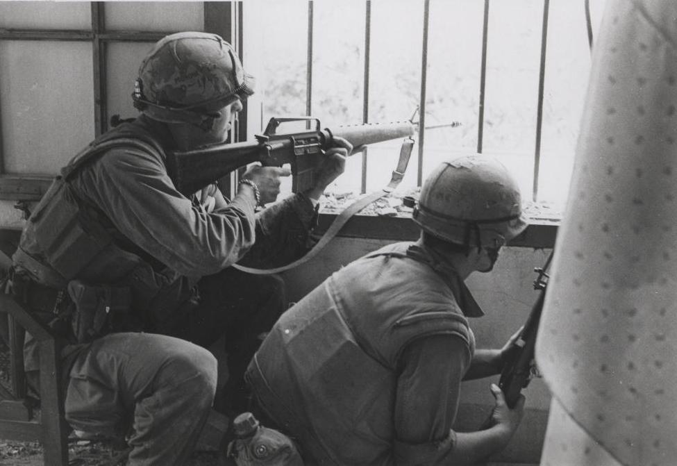 A U.S. Marine aims an M16 rifle out a house window during the Battle of Huế in 1968 image